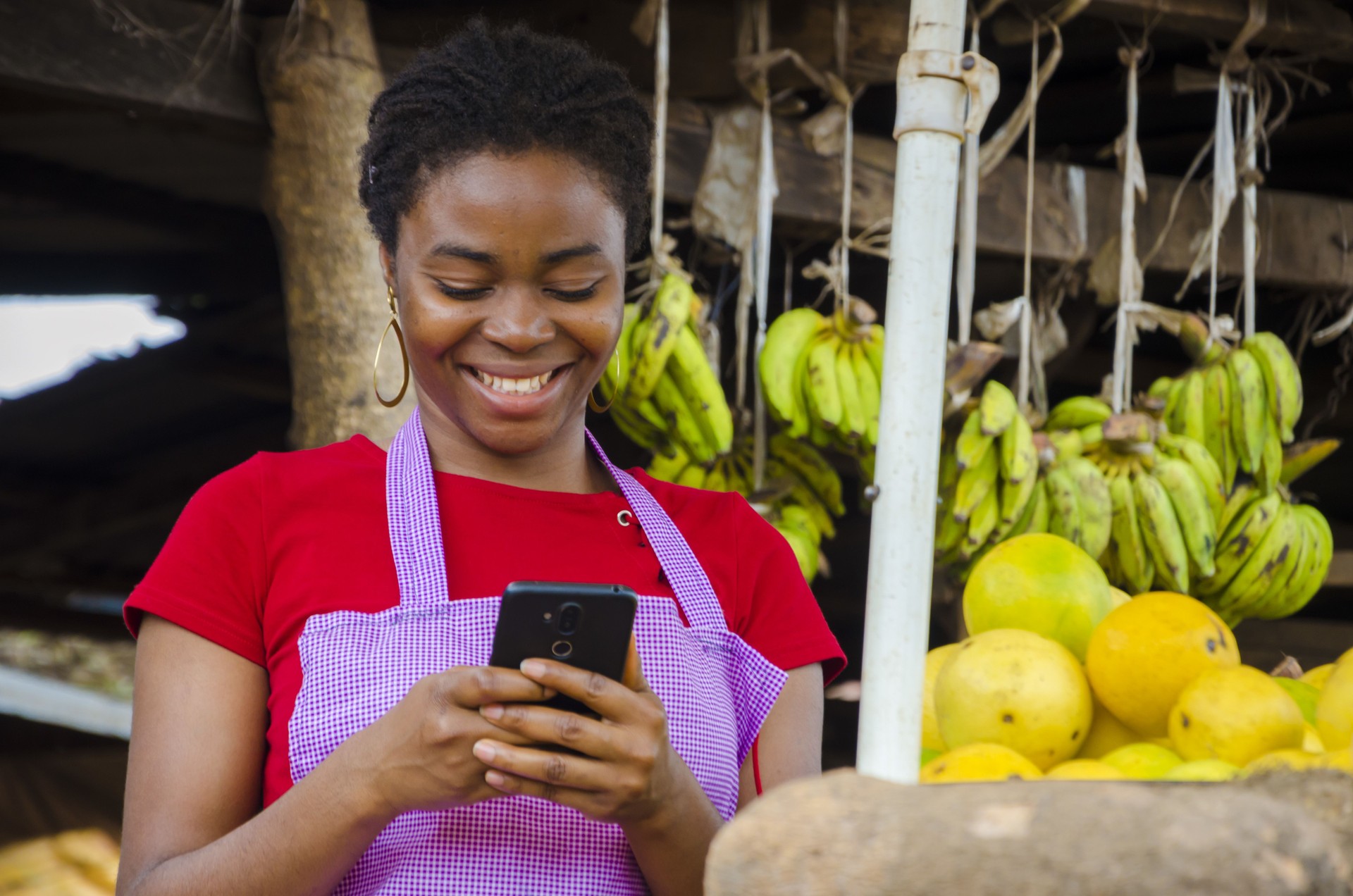 a young beautiful african market woman feeling happy about what she saw on her cellphone